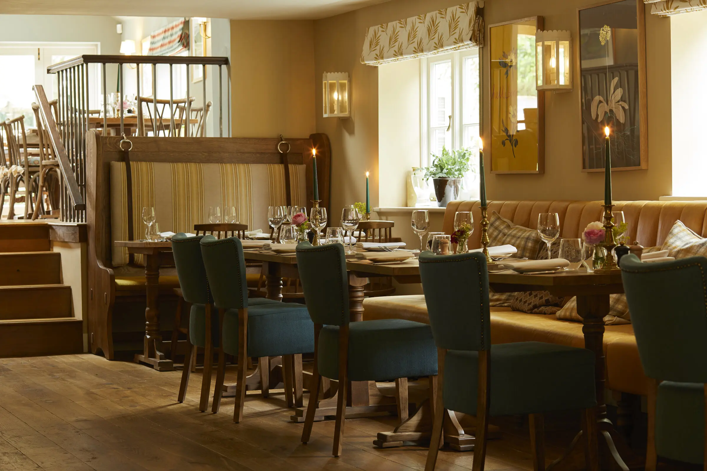 The long dining table laid with candles and green velvet chairs