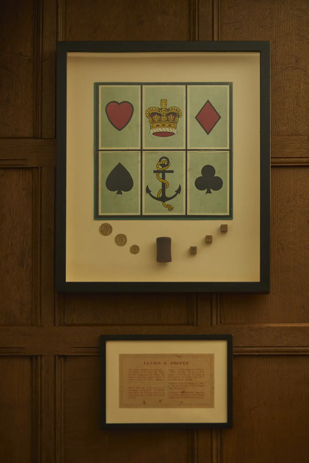 A framed Crown & Anchor board on the oak panelling
