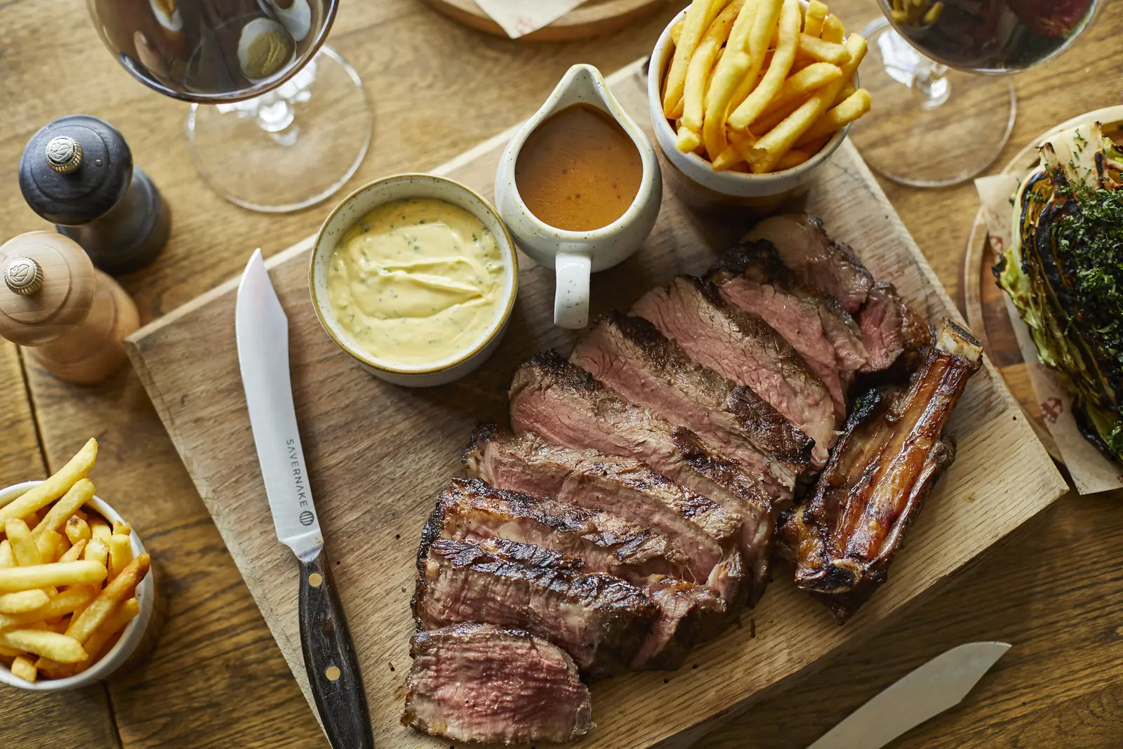 Sliced steak with chips and béarnaise on a board